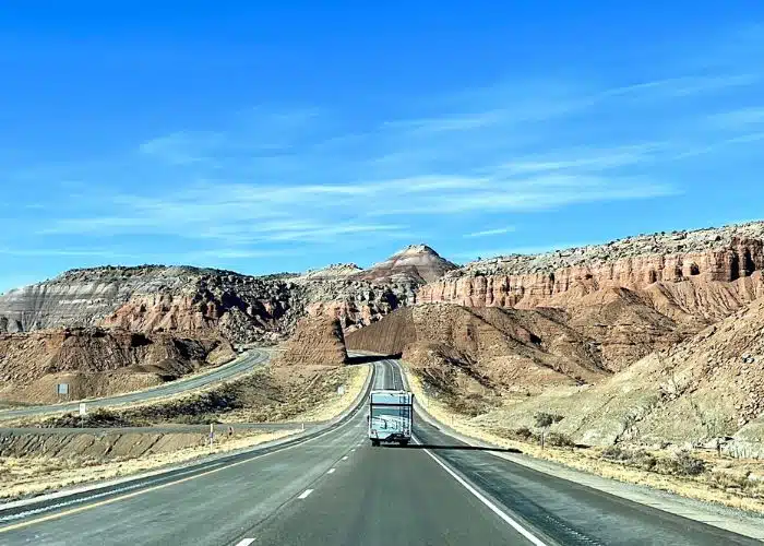 class c motorhome drives toward towering rock cliffs in utah