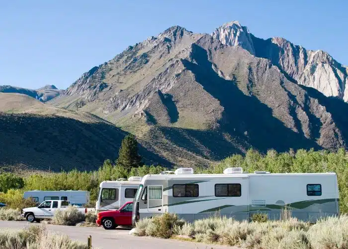 rvs parked in campsites with large rocky mountain behind
