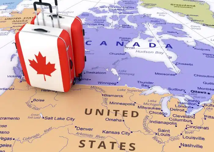 canada flag suitcases at border of usa canada map