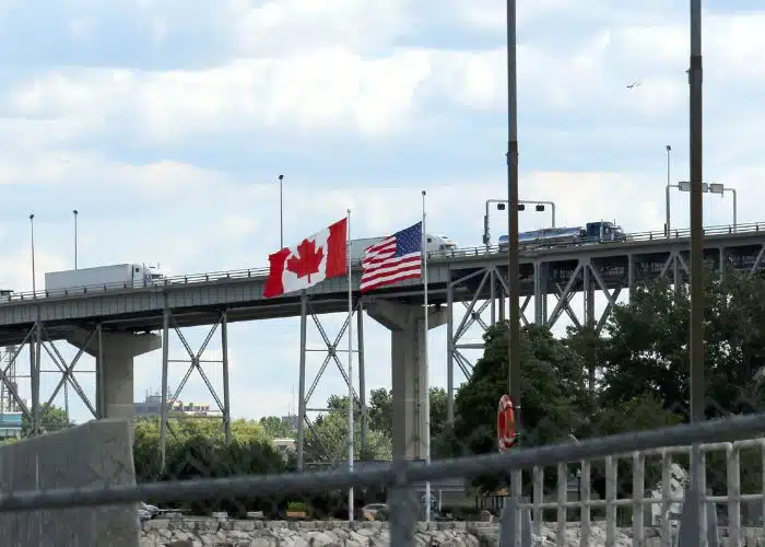 canadian border crossing into usa vehicles on bridge and usa canada flags