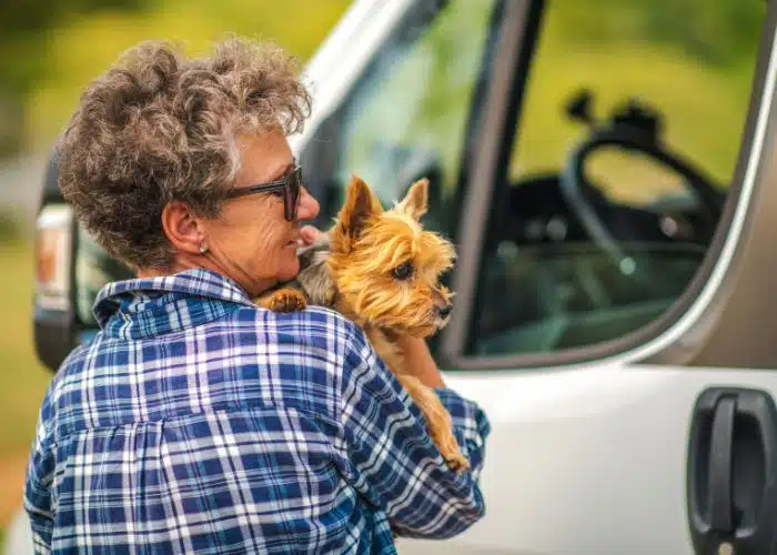 woman holds small dog outside of rv