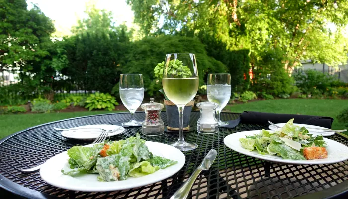 beautiful garden background behind table with salads and wine