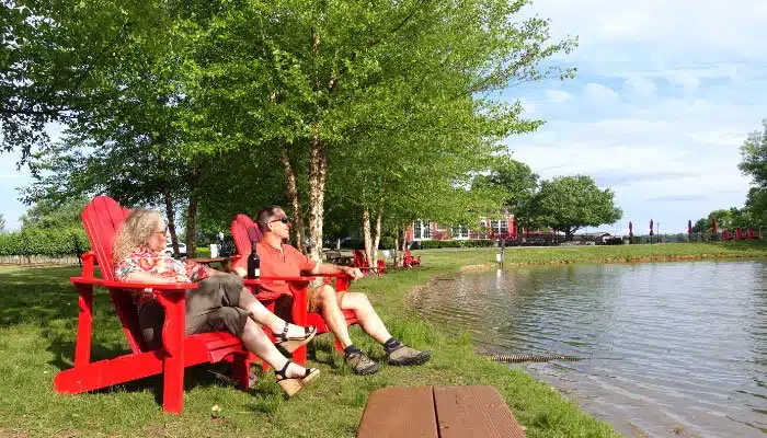 couple in adriondak chairs next to pond at doukenie winery in virginia