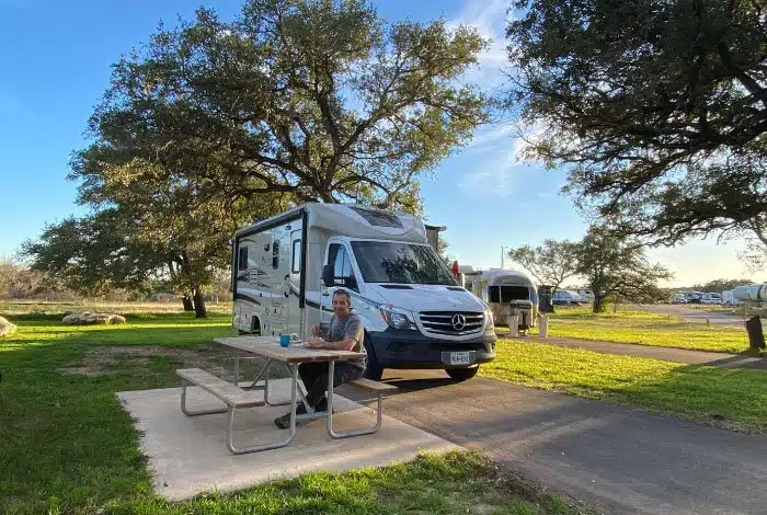 woman at picnic table with RV Rental in background