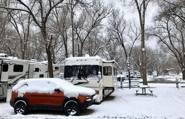 Snow covered RV and Jeep in campground