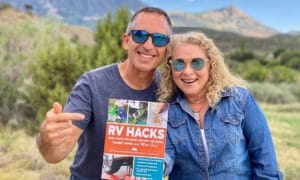 MARC And julie bennett of rvlove holding RV HACKS book with mountain backdrop