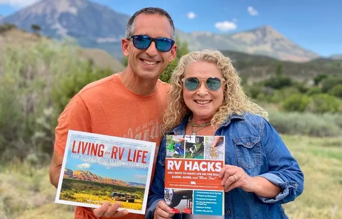 marc and julie of RVlove hold their 2 books with mountain backdrop