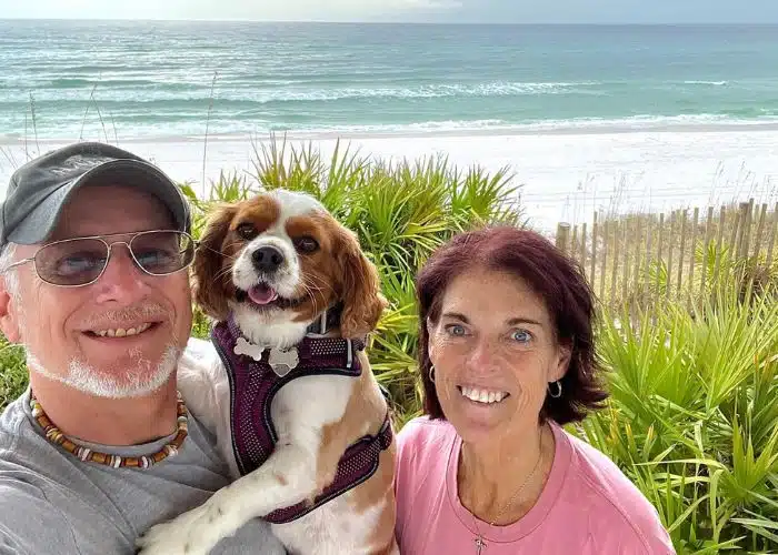 couple and dog with beach in background