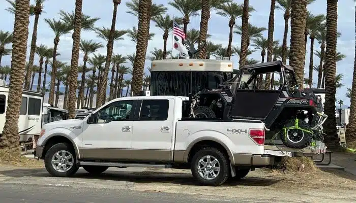 white 4 door truck with side by side atv in bed