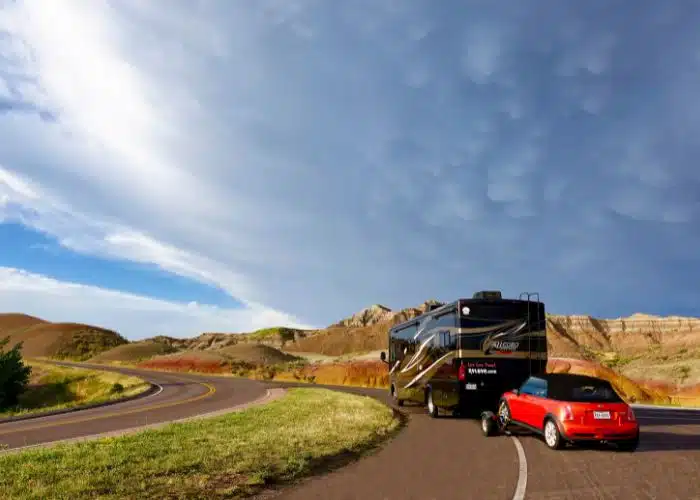 tiffin motorhome tows mini on dolly scenic south dakota badlands backdrop