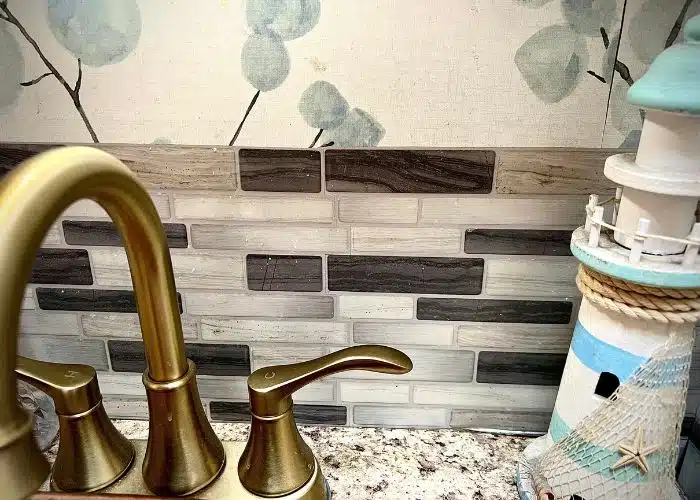 close up of RV bathroom with faucet, peel and stick backsplash and lighthouse decor