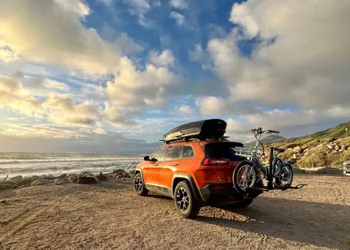 jeep with bike parked by beach sun hitting