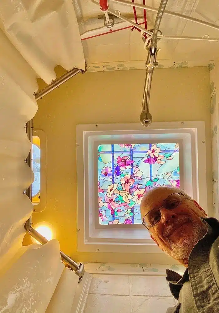man smiles in photo looking up at him and stained glass-look skylight
