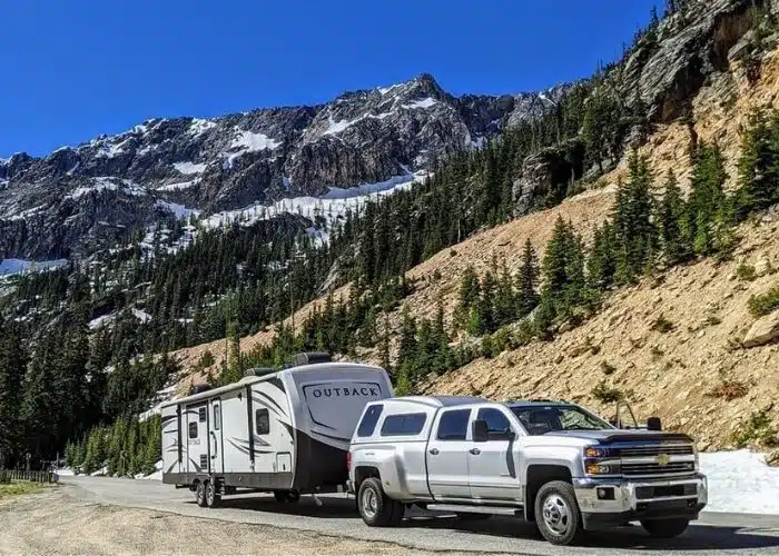 Photo Credit_ Pat Knoer-Jennette truck and travel trailer parked on side of road surrounded by trees and mountains