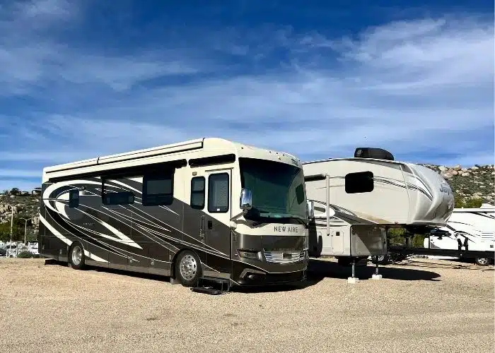 class a motorhome and fifth wheel parked in dirt rv storage lot