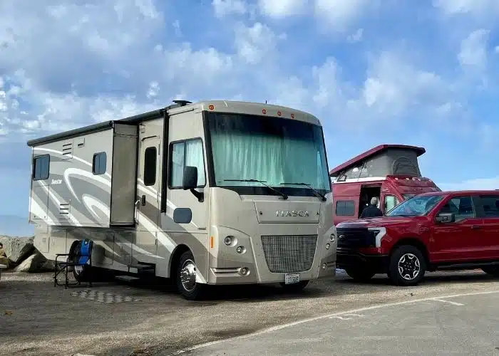 class a motorhome van and tuck parked with blue skies above