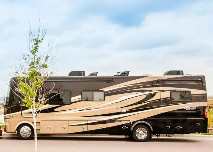 class a tiffin allegro motorhome parked side view tree in forefront blue skies above