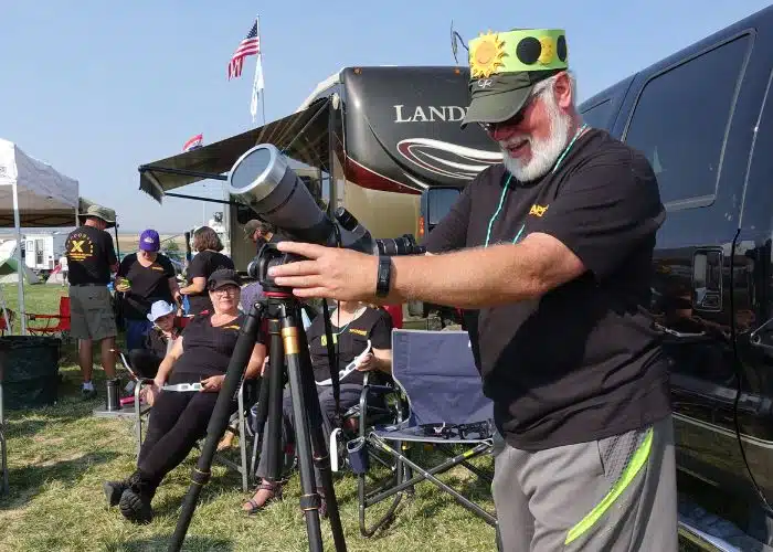 Man looks through telescope with RVs behind