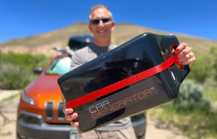 Man holding car generator in front of Jeep arms stretched out