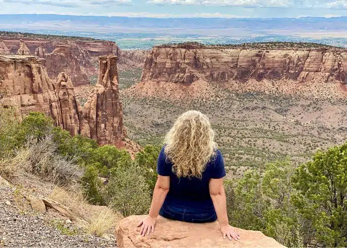 woman sitting of edge of canyon in colorado national monument