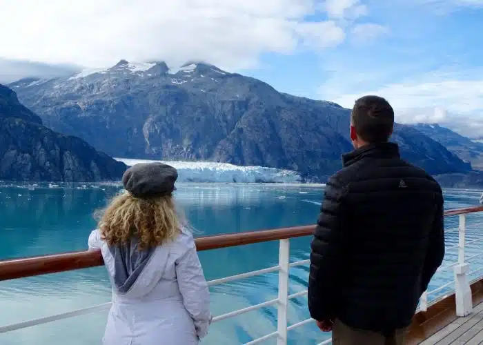 couple stands at cruise ship rail in glacier bay alaska