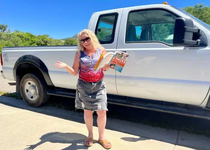 julie stands in front of truck with rv hacks book