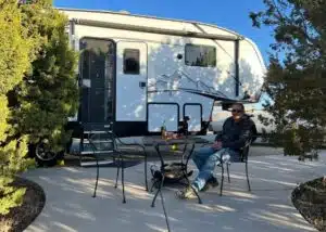marc relaxes on concrete patio outside of RV by trees at Santa Fe Skies RV Park NM