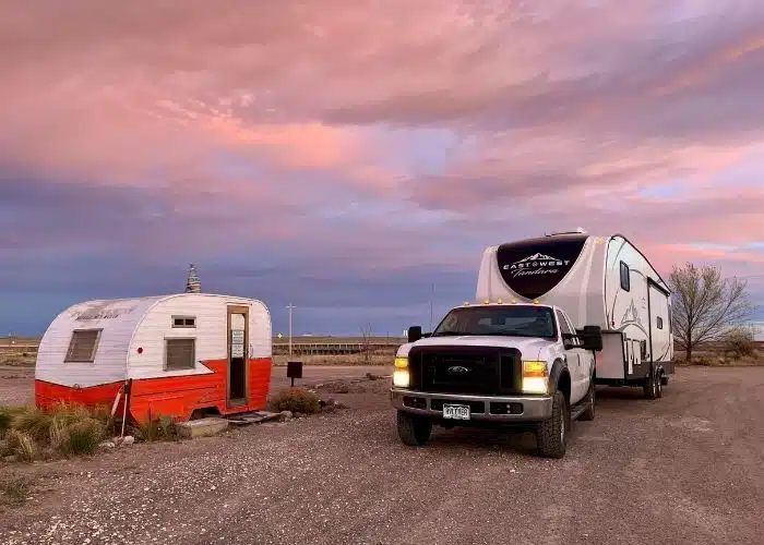 pink sky dusk shot of truck and fifth wheel by vintage camper check in office at Tumble In Marfa TX