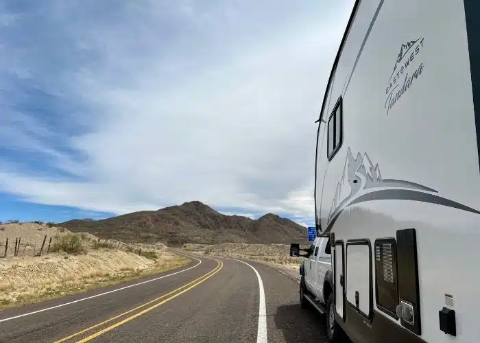 side view of rv on side of curved road with mountain ahead